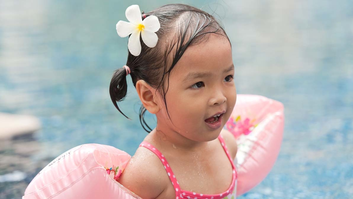 Young girl in pool with armbands on
