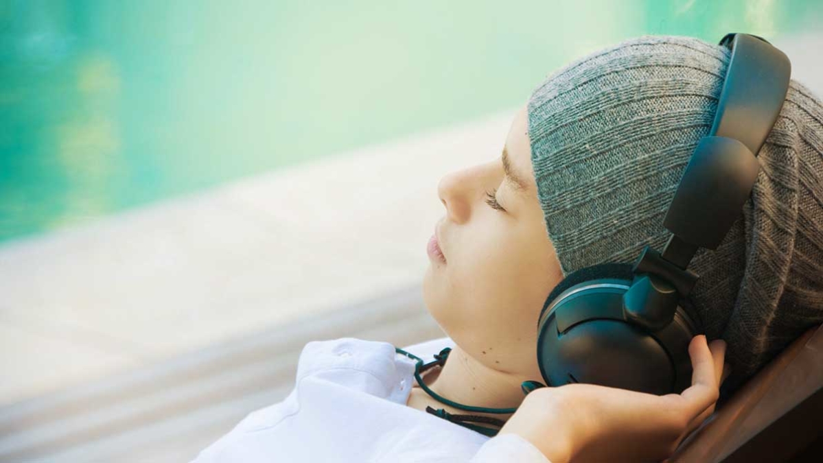 young adult listening to music with headphones by window
